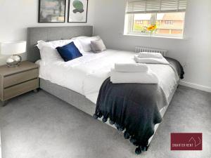 Farnborough - Newly Refurbished 2 Bedroom Home في Blackwater: غرفة نوم بسرير كبير مع شراشف بيضاء ومخدات زرقاء