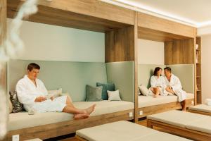 three people sitting on bunk beds in a room at Wellnesshotel Sanct Bernhard in Bad Ditzenbach