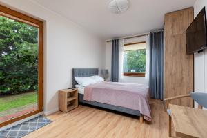 a bedroom with a bed and a large window at Domki i Pokoje -WISIENKA in Rewal