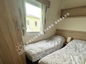 two beds in a bedroom with a window at Cosy 2 bed @ Seal Bay, Selsey in Selsey