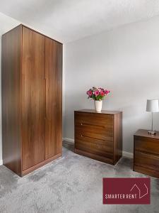 a room with a wooden cabinet with a vase of flowers on it at Finchampstead, 1 Bedroom House with garden in Finchampstead