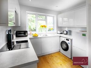 uma cozinha branca com um lavatório e uma máquina de lavar louça em Sunninghill Village - 2 Bed - Parking and garden em Ascot