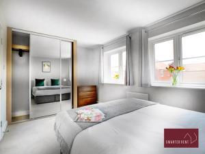 um quarto com uma grande cama branca e 2 janelas em Wokingham - 2 Bed House with parking and garden em Wokingham
