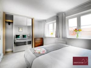 a bedroom with a large white bed and two windows at Wokingham - 2 Bed House with parking and garden in Wokingham