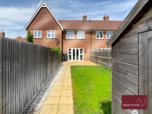 a house with a wooden fence and a gate at Wokingham - 2 Bed House with parking and garden in Wokingham