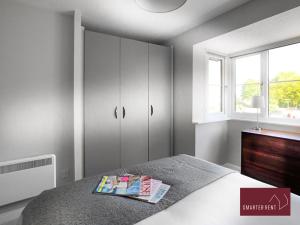 a bedroom with a bed and a cabinet and a window at Wokingham - 2 Bed Stylish House, Central - Parking in Wokingham