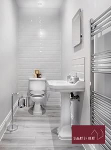 Baño blanco con lavabo y aseo en Thames Ditton - Luxury 4 Bedroom House - Garden and Parking, en Thames Ditton