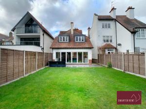 una casa con una valla y un patio verde en Thames Ditton - Luxury 4 Bedroom House - Garden and Parking, en Thames Ditton