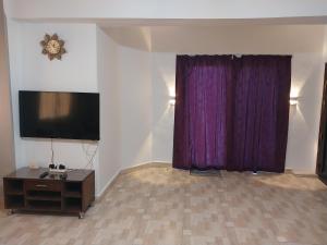 ein Wohnzimmer mit Fernseher und lila Vorhängen in der Unterkunft Jasmine villa in Hurghada
