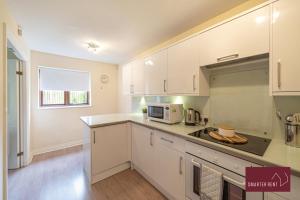 een keuken met witte kasten en een magnetron bij Maidenhead - 2 Bed & parking in Maidenhead