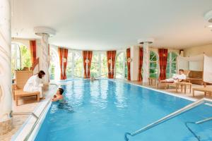 a family playing in a swimming pool in a building at Wellnesshotel Sanct Bernhard in Bad Ditzenbach