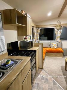 Une caravane comprend une cuisine équipée de plaques de cuisson. dans l'établissement 2 Bed Chalet - Sleeps 5 - Garden - Parking - Wifi, à Prestatyn