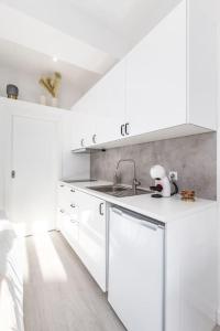 een witte keuken met witte kasten en een wastafel bij Studio de luxo no Porto - T0 in Porto