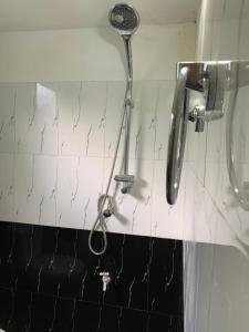 La salle de bains est pourvue d'un pommeau de douche sur un mur carrelé. dans l'établissement Chill House safari resort, à Uda Walawe
