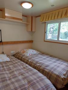 a bedroom with two beds and a window at Camping L'Enclave mobil-home in Estavar