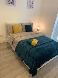 a bed with a blue blanket and yellow pillows at Luxury 2 Bedroom apartment in King's Cross in London