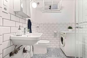 een witte badkamer met een wastafel en een wasmachine bij Cosy Studio 10 min Center in Bratislava