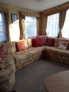 - un grand canapé dans le salon doté de fenêtres dans l'établissement Carnival Our lovely home from home, à Great Yarmouth