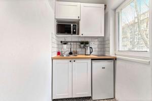 een witte keuken met een wastafel en een magnetron bij Cosy Studio 10 min Center in Bratislava