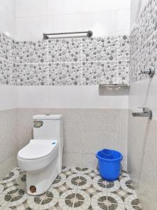 a bathroom with a toilet and a blue bucket at Munroe La Casa in Kollam