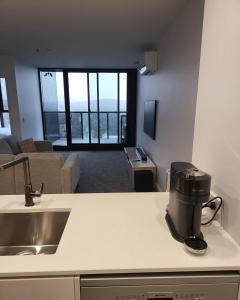 a kitchen with a coffee maker on a counter next to a living room at 2 Bedroom Apartment on Nightfall in Belconnen