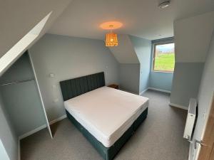 a small bedroom with a bed and a window at Ashwood House at Thoulstone Park in Corsley