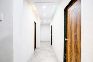 an empty corridor with a wooden door and white walls at Hotel Apollo in Ahmedabad