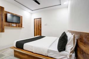 Hotel Apollo في أحمد آباد: غرفة نوم مع سرير وتلفزيون على الحائط