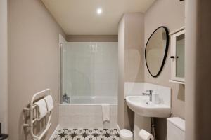 a white bathroom with a sink and a bath tub at The Deptford Hideout - Lovely 1BDR Flat in London
