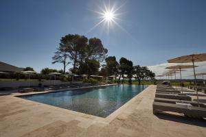 a large swimming pool with chairs and umbrellas at Château St Pierre de Serjac in Puissalicon