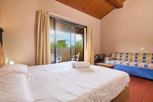 a bedroom with a bed and a couch and a window at Hotel Zì Martino in Castagneto Carducci