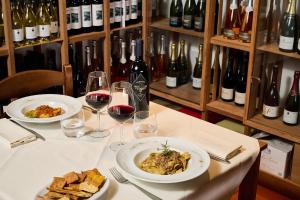 a table with two plates of food and wine glasses at Hotel Z&igrave; Martino in Castagneto Carducci