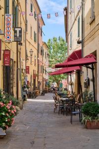 pusta ulica ze stołami, krzesłami i parasolami w obiekcie Hotel Zì Martino w mieście Castagneto Carducci