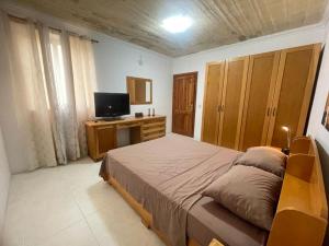 een slaapkamer met een groot bed en een televisie bij Mellieha Apartment in Mellieħa