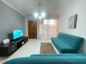 ein Wohnzimmer mit einem blauen Sofa und einem TV in der Unterkunft Mellieha Apartment in Mellieħa