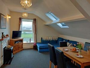 a living room with a blue couch and a table at Trem Y Mor - Edge of the Sea in Tywyn