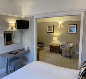 a hotel room with a bedroom with a bed and a desk at Brigstock House in Llandudno