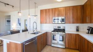 une cuisine avec des appareils électroménagers en acier inoxydable et des armoires en bois dans l'établissement Landing Modern Apartment with Amazing Amenities (ID2542X13), à San Diego