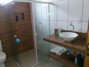 een badkamer met een glazen douche en een wastafel bij Casa para temporada em Alto Caparaó MG in Caparaó Velho