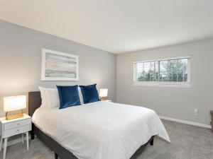1 dormitorio con 1 cama blanca grande con almohadas azules en Landing Modern Apartment with Amazing Amenities (ID2754X85), en Madison