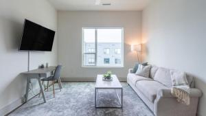 Sala de estar blanca con sofá y mesa en Landing Modern Apartment with Amazing Amenities (ID2441X04) en Pittsburgh