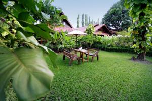 a table and benches with an umbrella in a yard at Smile House - Fisherman Village in Bophut