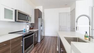 cocina con paredes blancas y suelo de madera en Landing Modern Apartment with Amazing Amenities (ID2441X04) en Pittsburgh