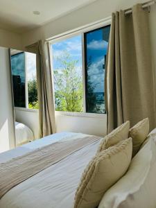 1 dormitorio con cama con almohadas y ventana en Lazzlla beachside studio apartments en Hulhumale