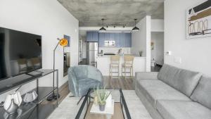 a living room with a gray couch and a kitchen at Landing - Modern Apartment with Amazing Amenities (ID1401X750) in Nashville