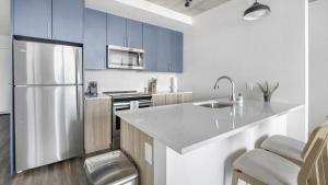 een keuken met blauwe kasten en een roestvrijstalen koelkast bij Landing - Modern Apartment with Amazing Amenities (ID1401X750) in Nashville