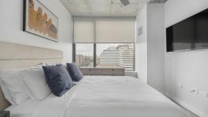 a white bedroom with a large bed with blue pillows at Landing - Modern Apartment with Amazing Amenities (ID1401X750) in Nashville