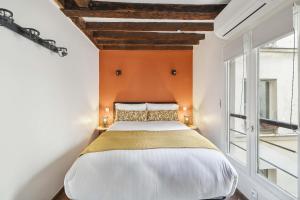 a bedroom with a large bed with an orange wall at Gentilhomme in Paris