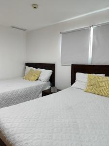 2 łóżka w sypialni z białymi i żółtymi poduszkami w obiekcie Vista marina Marbella w mieście Juan Pedro