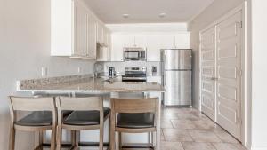 a kitchen with white cabinets and a island with bar stools at Landing Modern Apartment with Amazing Amenities (ID8418X24) in Bentonville